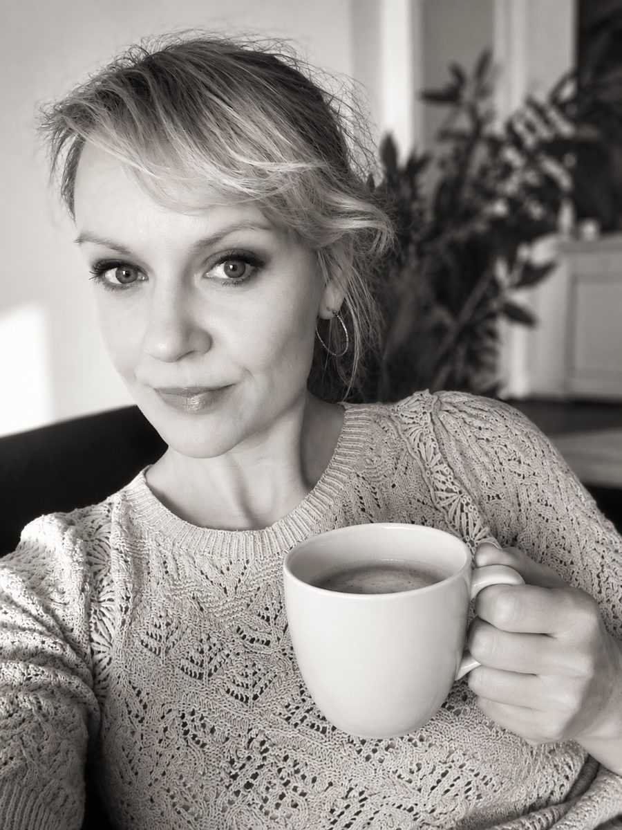 Bettina Kochheim hält lächelnd eine Kaffeetasse in die Kamera, passend zur Einladung auf einen virtuellen Kaffee.