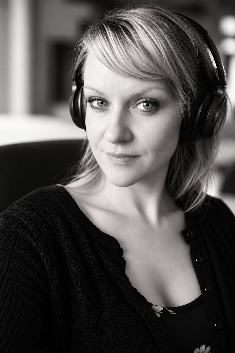 Bettina Kochheim mit Over-Ear-Kopfhörern im Porträt, den Blick direkt in die Kamera gerichtet.